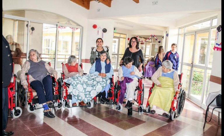 Mónica Galleguillos, terapeuta ocupacional; y Ximena Salinas, junto a  residentes del hogar.